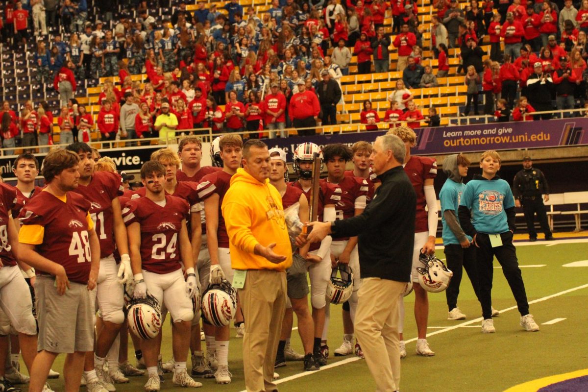 Head football coach Greg Bonnett is presented with the semi-final participant trophy after Saturday’s loss.
